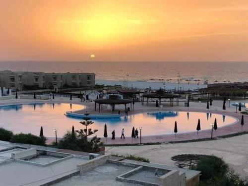 Blick auf ein Resort mit Sonnenuntergang über dem Meer in der Unterkunft شاليه الساحل الشمالي in Dawwār Shindī Fannūsh