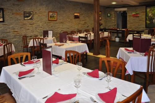 un ristorante con tavoli e sedie bianchi con tovaglioli rossi di A Reigada Hotel Restaurante a Grandas de Salime