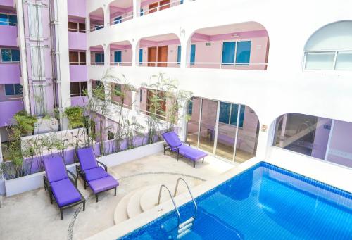 um apartamento com uma piscina e cadeiras roxas em Hotel Kavia em Cancún