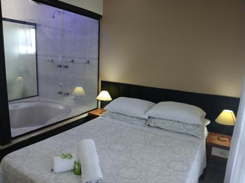 een slaapkamer met een bed en een bad en een bed met handdoeken bij Miragem Chalés in Serra Negra