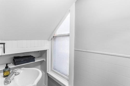 ein weißes Bad mit einem Waschbecken und einem Fenster in der Unterkunft Stylish 2bd, DT, Lndry & Prkng in Windsor
