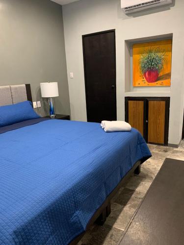 a bedroom with a blue bed and a painting on the wall at Residencial Edzna in Campeche