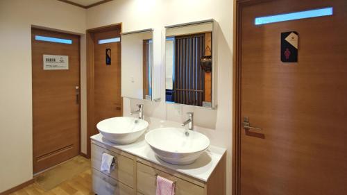 a bathroom with two sinks and a mirror at White House Onsen Guesthouse in Shiraoi