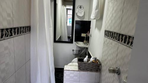 a white bathroom with a sink and a mirror at Apartamento cerca al centro y sitios turísticos in Bogotá