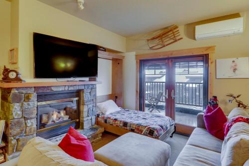 a living room with a fireplace and a flat screen tv at Ski-InandSki-Out Whitefish Escape with Balcony! in Whitefish