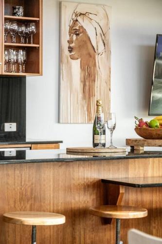 a bar with a bottle of wine and two stools at Sophie's Place ReLaunch - Luxury Penthouse in Byron Bay