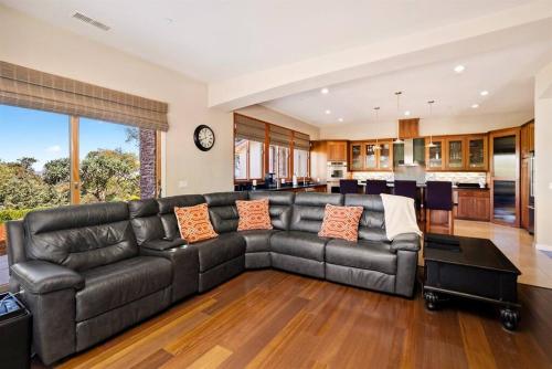a large living room with a black leather couch at Hilltop Vistas-Private Pool, Firepit, Views in Atascadero
