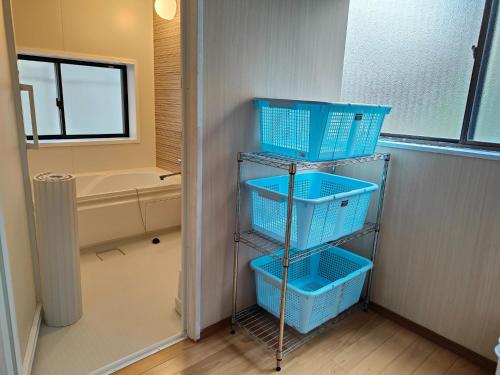 a shelf with blue baskets in a bathroom with a tub at Morita-ya Japanese style inn KujakuーVacation STAY 62460 in Tamana