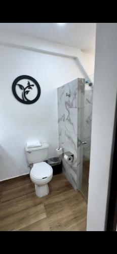 a bathroom with a toilet and a sign on the wall at Hotel del Alba Inn & Suites in Aguascalientes