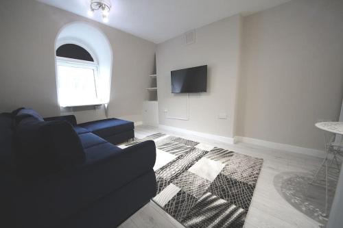 a living room with a blue couch and a tv at Cosy studio Victoria in London