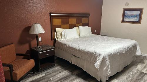 a bedroom with a bed and a lamp and a chair at Deluxe Inn Of Roswell in Roswell