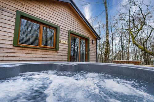 a hot tub in front of a house at Padley; woodland lodge with hot tub for 2-4 in the Staffordshire Moorlands in Oakamoor