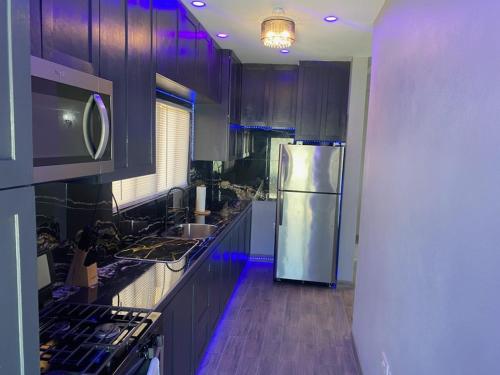 a kitchen with a stainless steel refrigerator and purple lighting at Delta Alpha Apartments in Calliste Land Settlement