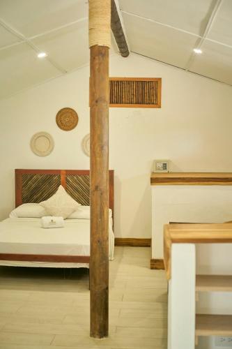 a bedroom with a bed and a wooden pole at Mangata Beach in Cartagena de Indias