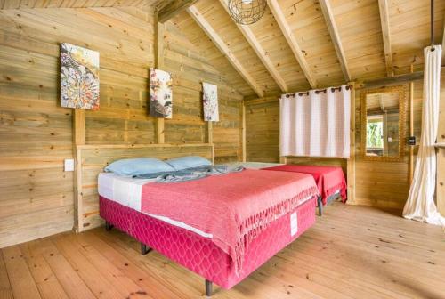 een slaapkamer met 2 bedden in een blokhut bij Sonhos do Rosa pousada in Praia do Rosa