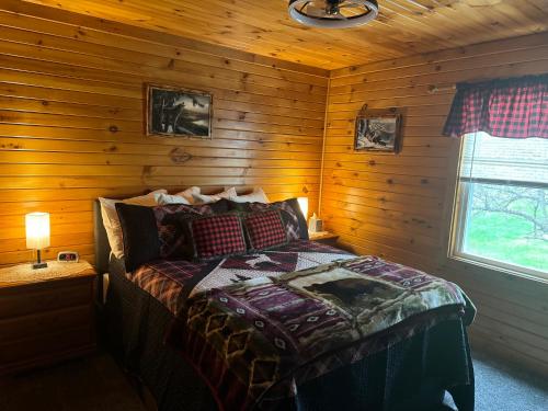 een slaapkamer met een bed in een blokhut bij The Lazy Bear Cabin in Long Lake