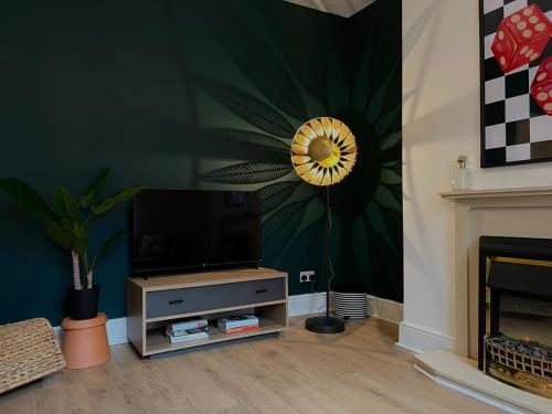 una sala de estar con TV y una flor en la pared en Quaint 2Bed House near Wigan Centre en Ince-in-Makerfield