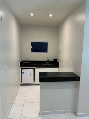 Apartamento localizado em condomínio fechad0 em Barra Grande - PI في بارنايبا: مطبخ أبيض مع كونتر أسود ومغسلة