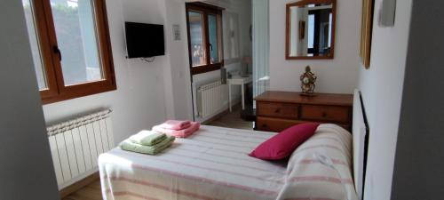 Un dormitorio con una cama con almohadas rosas y verdes. en MONTESCLAROS Apartamento de 2 dormitorios, en Cerceda