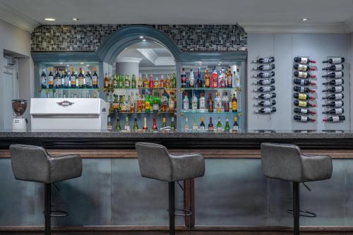 a bar with three chairs in front of it at Holiday Inn Johannesburg OR Tambo Airport Hotel by IHG in Kempton Park
