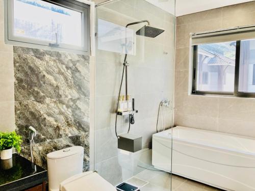 La salle de bains est pourvue d'une baignoire, de toilettes et d'une fenêtre. dans l'établissement V3E02 Dahlia villa - khu nghỉ dưỡng Sonasea Vân Đồn, à Cái Rồng