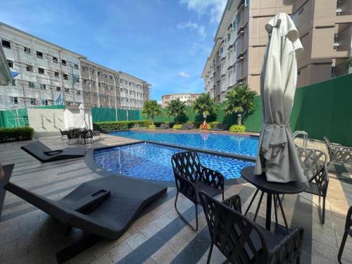 a swimming pool with chairs and a umbrella on a patio at MJC's Stay and Relax in Marilao