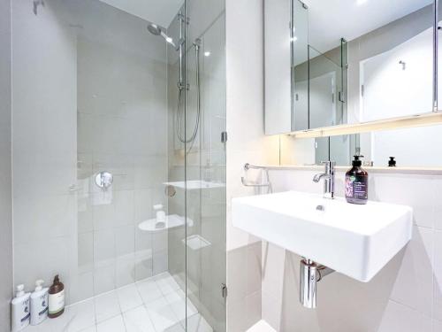 a white bathroom with a sink and a shower at Brilliant Victoria Harbour Waterfront in Melbourne