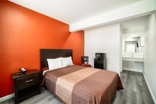 Bell Manor Motel في Bell: غرفة نوم بسرير بحائط برتقالي
