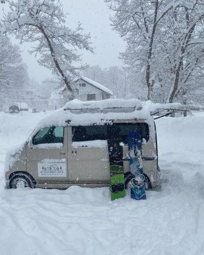a van covered in snow in a yard at Myoko Forest Lodge in Myoko
