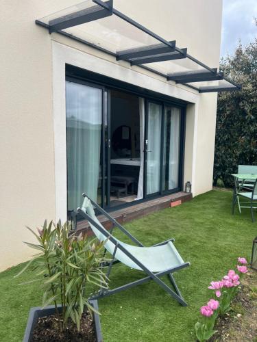 a chair on a lawn in front of a house at Suite romantique avec Spa et filet suspendu in Auteuil