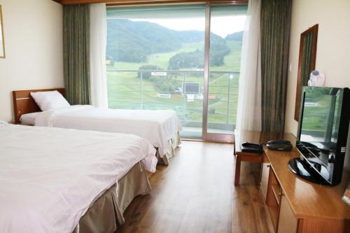 a hotel room with two beds and a flat screen tv at Wellihilli Park Resort in Hoengsong