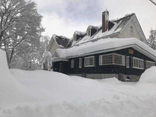 a house covered in snow with a pile of snow at Myoko Forest Lodge in Myoko