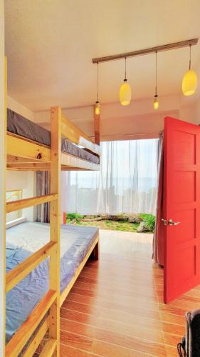 a bedroom with two bunk beds and a red door at Tiny House's Seafront Room in Camotes Island in Esperanza