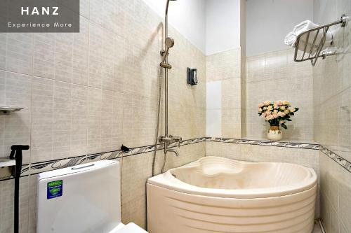 胡志明市的住宿－HANZ Vivianne Hotel，一间带卫生间和花瓶的浴室