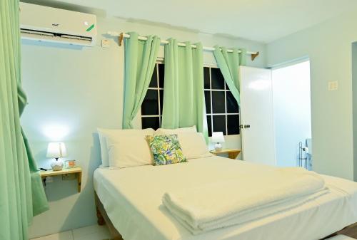 Schlafzimmer mit einem Bett und grünen Vorhängen in der Unterkunft Sands Great Bay in Treasure Beach