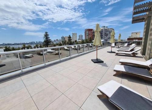 a patio with lounge chairs and umbrellas on a roof at Proamar in Punta del Este