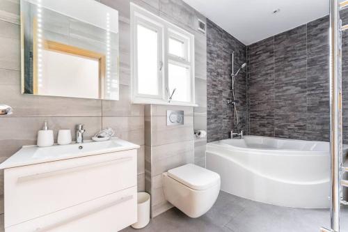 baño blanco con bañera, aseo y lavamanos en Vibrant Urban Escape, Family Friendly - Sleeps 8!, en Londres