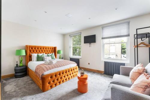 1 dormitorio con 1 cama grande de color naranja y 1 sofá en Vibrant Urban Escape, Family Friendly - Sleeps 8!, en Londres