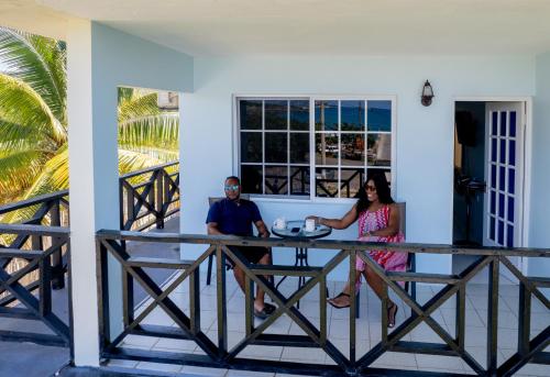 un hombre y una mujer sentados en una mesa en un porche en Sands Great Bay, en Treasure Beach