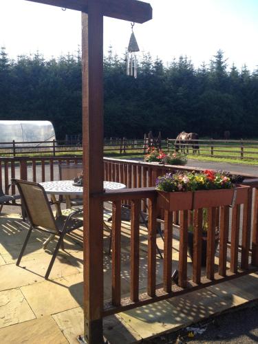 a wooden deck with a table and chairs and flowers at Yeats Lodge in Drumcliff