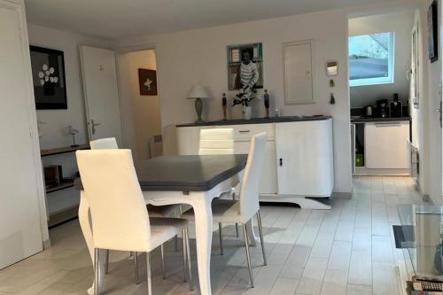 - une cuisine avec une table à manger et des chaises blanches dans l'établissement Small cottage for 4 people nestled in the heart of the dunes of Le Touquet, à Le Touquet-Paris-Plage