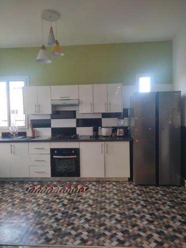 a kitchen with a stainless steel refrigerator and white cabinets at Résidence Ahitantsoa Majunga in Mahajanga