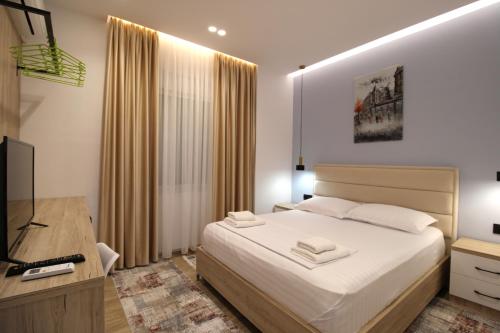 a bedroom with a bed and a desk and a television at Sarande Luxury Central apartment Reni Risi in Sarandë