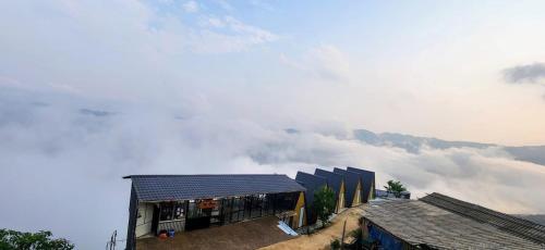 a building on top of a mountain with clouds in the background at Mây House – Sống Lưng Khủng Long in Bắc Yên