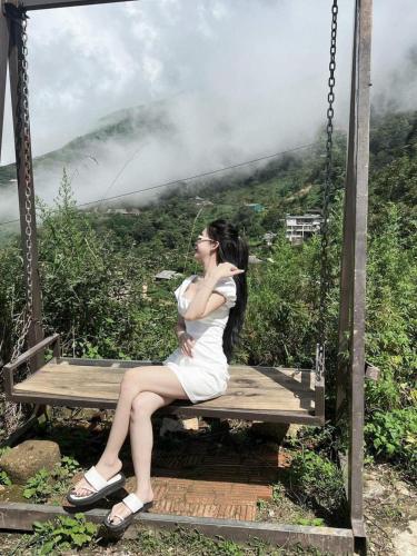 a woman sitting on a swing overlooking a mountain at Mây House – Sống Lưng Khủng Long in Bắc Yên