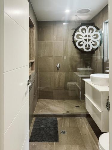 a bathroom with a shower with a sink and a toilet at Kookaburra Cottage at On Burgum Pond in Maleny