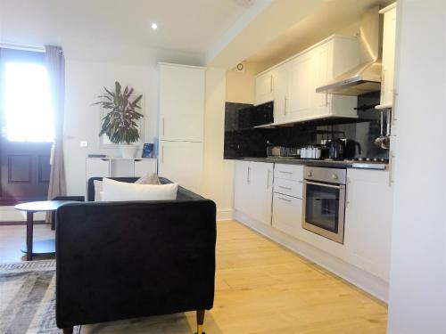a kitchen with white cabinets and a black chair at InstaLet Apartments I Wigan Central I Free Parking in Wigan