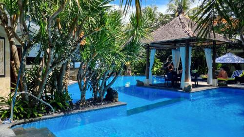 a swimming pool with a gazebo and palm trees at Apartment Nine at the Bayshore Resort Candidasa in Candidasa