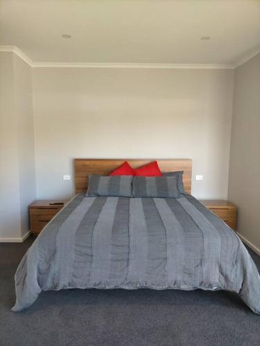 Un dormitorio con una cama grande con almohadas rojas. en Stay and Play Golf, en Worrolong