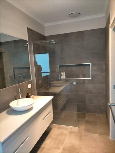 Un baño con lavabo, espejo y ducha. en Stay and Play Golf, en Worrolong